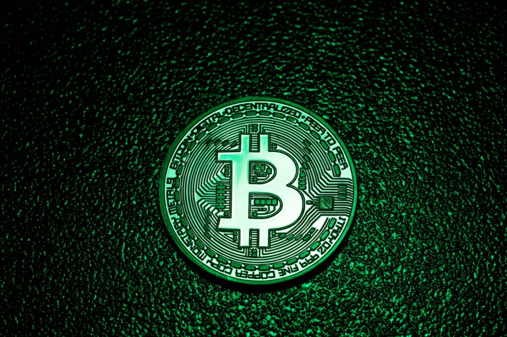 A coin with bitcoin logo in a green lighting.