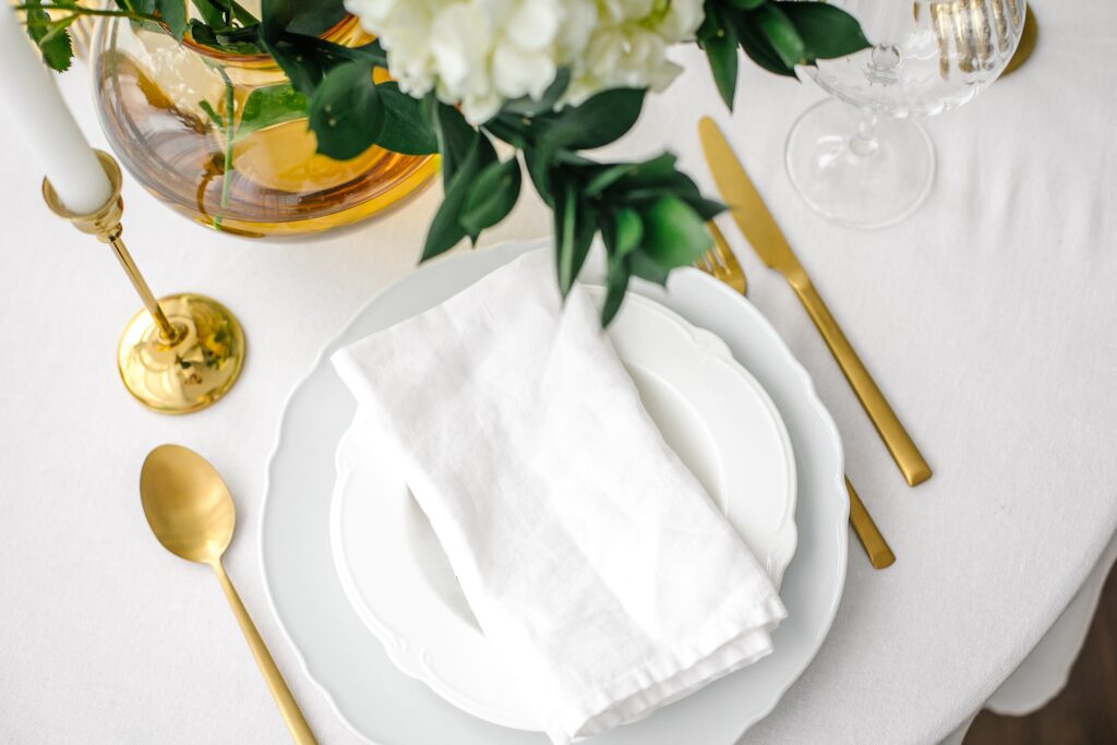 Elegance classic table setting with white dishes, gold cutlery and hydrangea flower